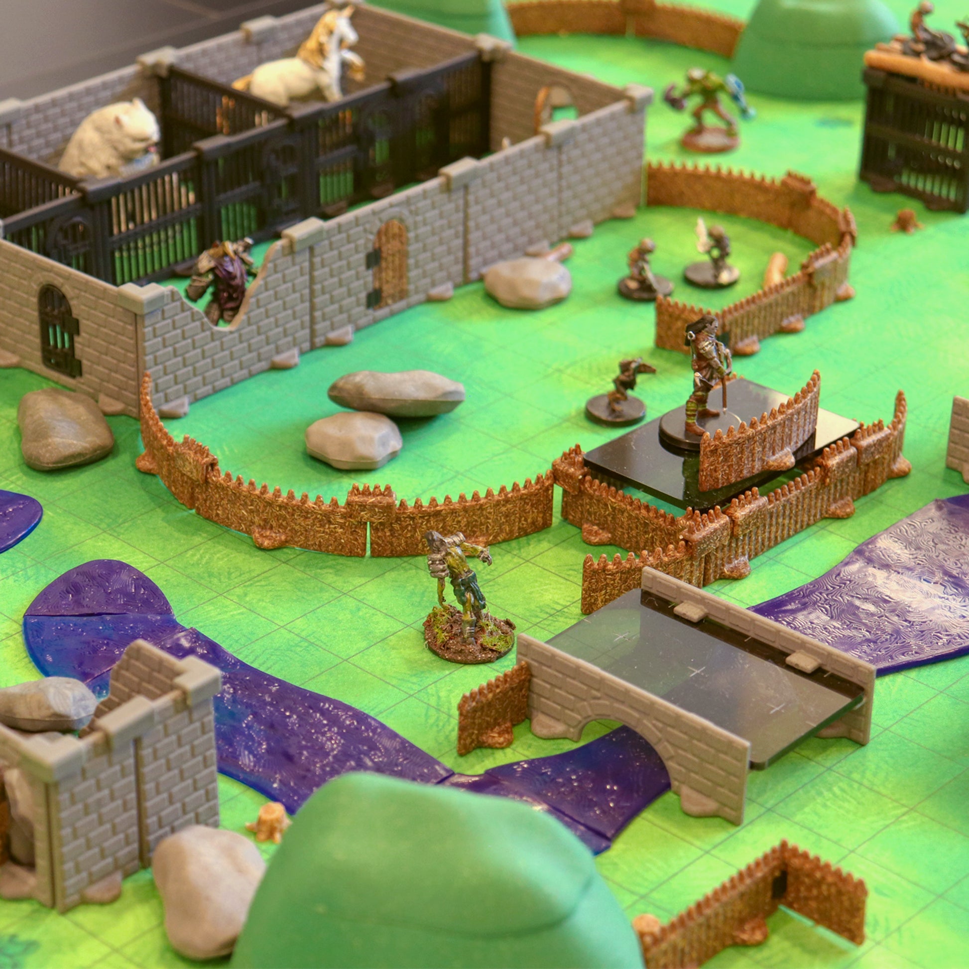 Scene showing fantasy miniatures positioned near the palisade fencing sections included in the Bandit Camp Adventure Set, demonstrating the modular walls used to create an outdoor, fortified encampment.