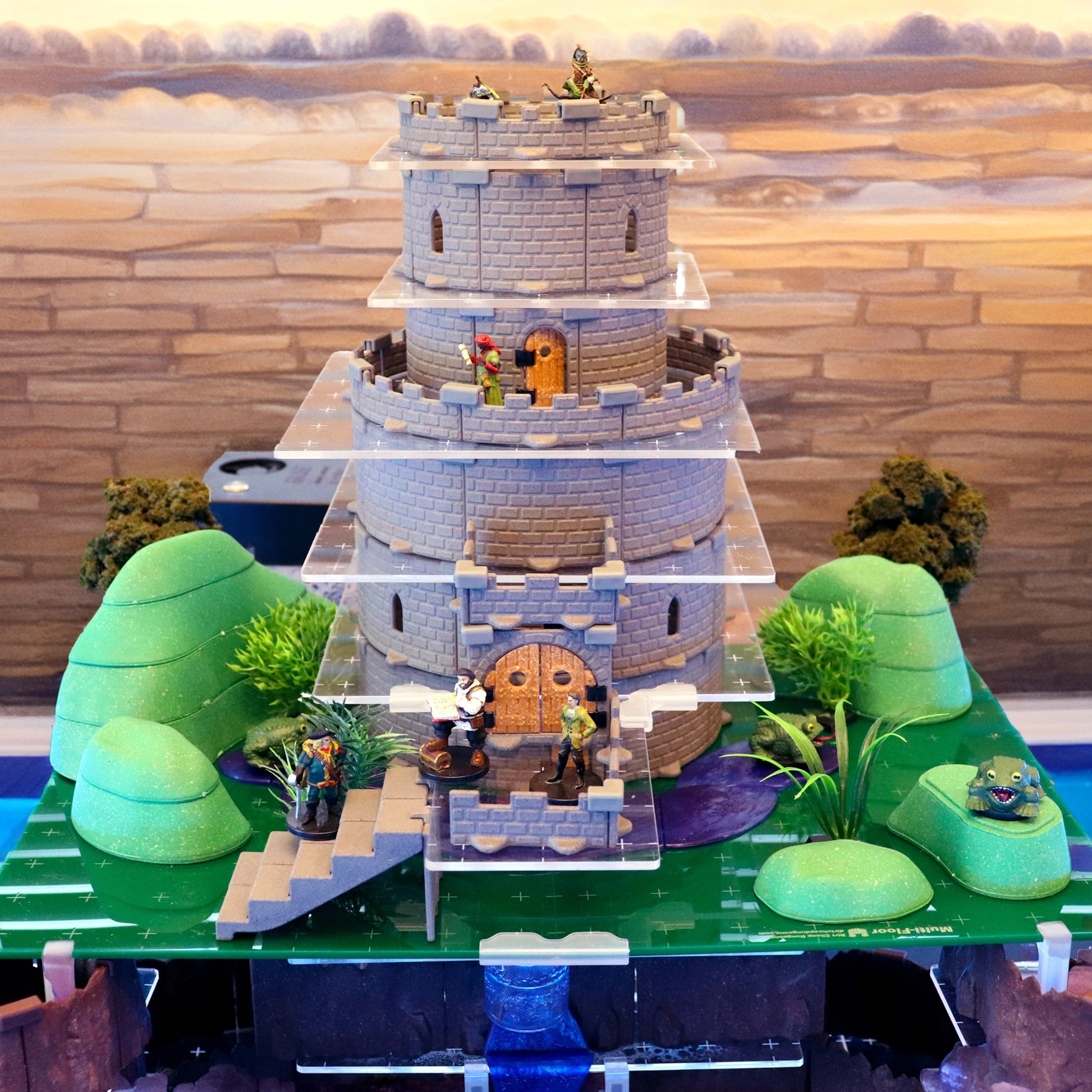 A unique setup combining the Gnoll Terrain Set's green modular hills with a multi-level castle from the Wizards Tower Core Set, demonstrating how outdoor terrain can augment vertical castle builds for D&D scenarios.