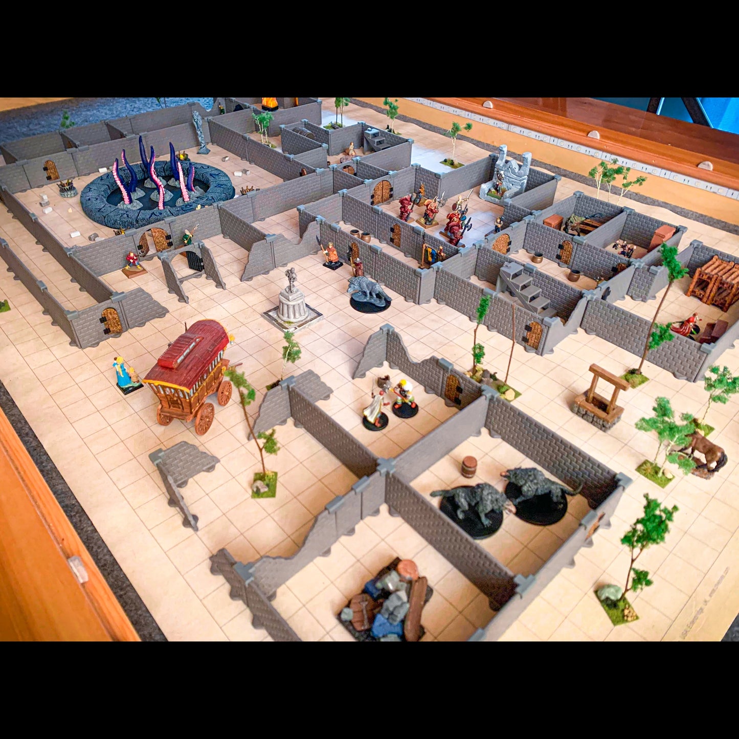 Close-up of an extensive, detailed Knight core dungeon set build on a map, featuring various miniatures, scatter terrain (wagon, well, statue), and unique room configurations.