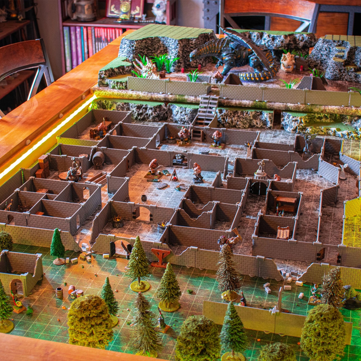 Wide overhead view of a massive Knight modular dungeon set build on a gaming table, featuring a large dragon and other miniatures, trees, and detailed rooms in an epic tabletop RPG adventure scene.