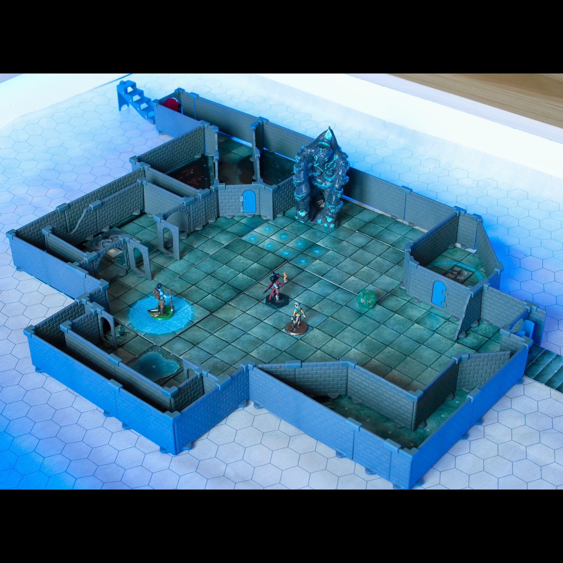 Wide view of a combat scene built using the Rogue set and diagonal wall pieces from the Diagonal Wall Expansion, featuring a large golem miniature and adventurer miniatures on a blue battle map under bright lighting.