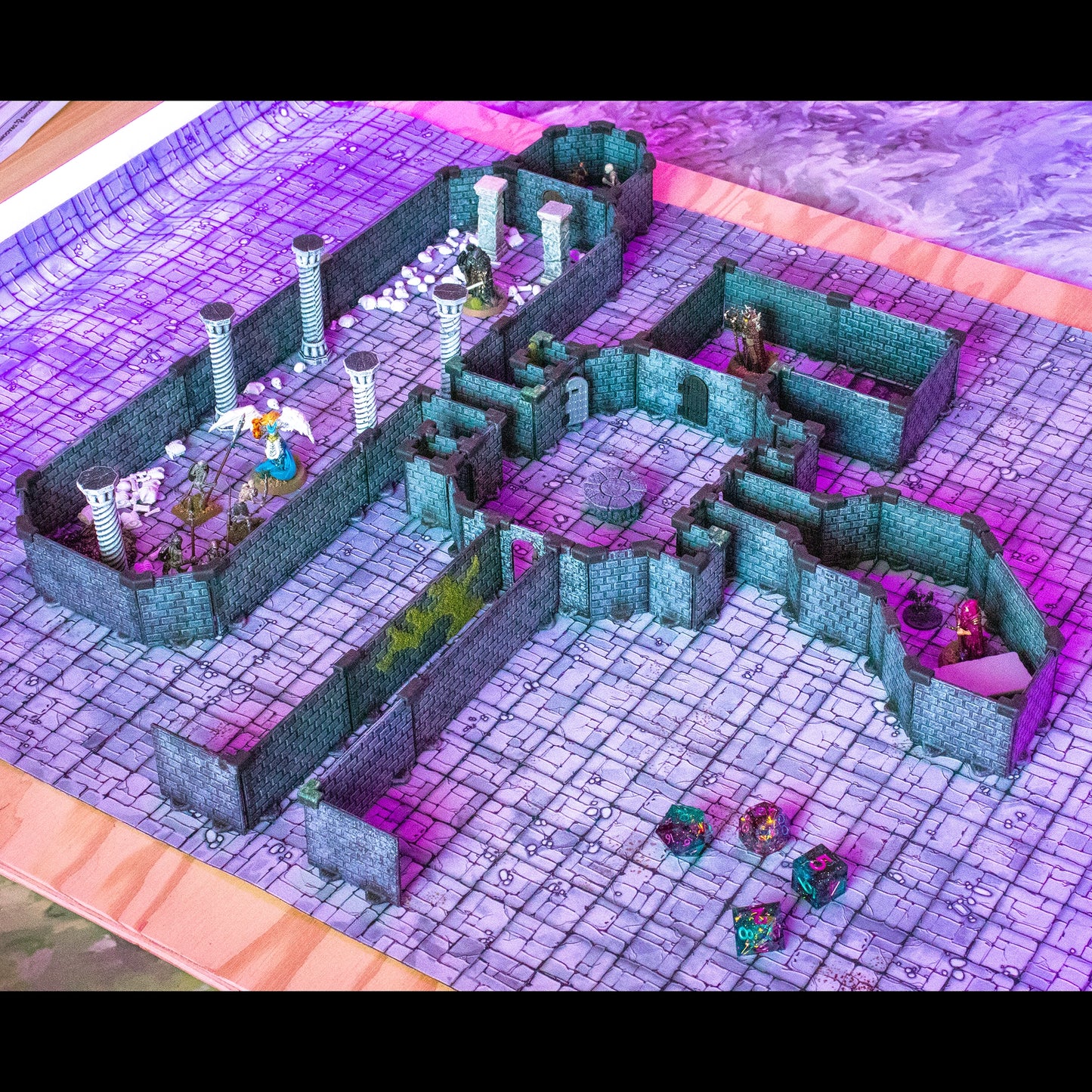 Atmospheric scene of the painted modular dungeon set in combination with a Diagonal Expansion Kit with a focus on diagonal wall placement, featuring fantasy miniatures, dice, pillars, and a purple-hued lighting scheme on a grey stone grid mat. Note: Retains Based on a battle location from Grim Hollow, with "diagonal walls" as a key visual feature.