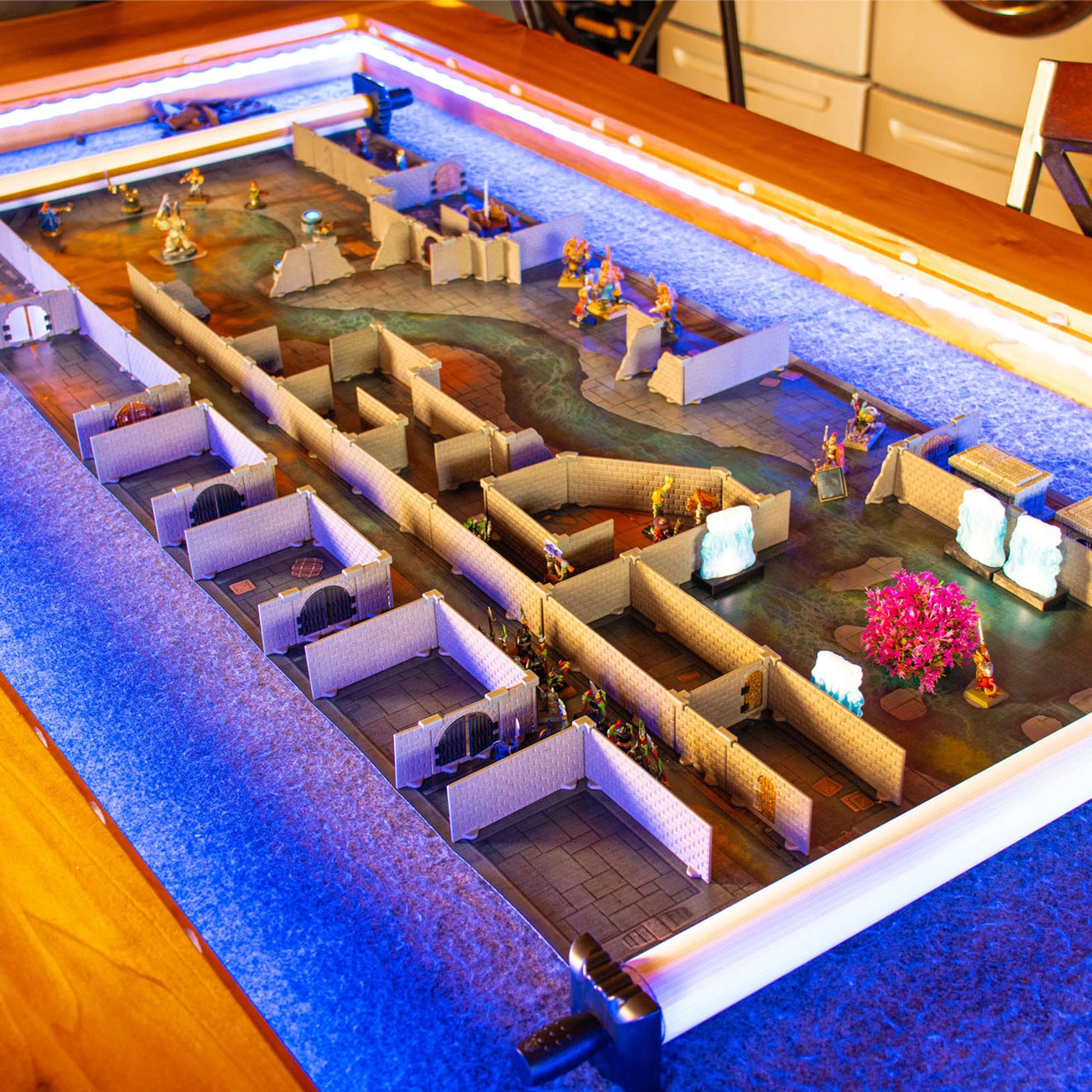 Wide view of an elaborate, long modular dungeon setup built with the Rogue full set on a gaming table, illuminated by blue lighting, showing multiple chambers and miniature combat scenes for a large-scale tabletop RPG adventure.