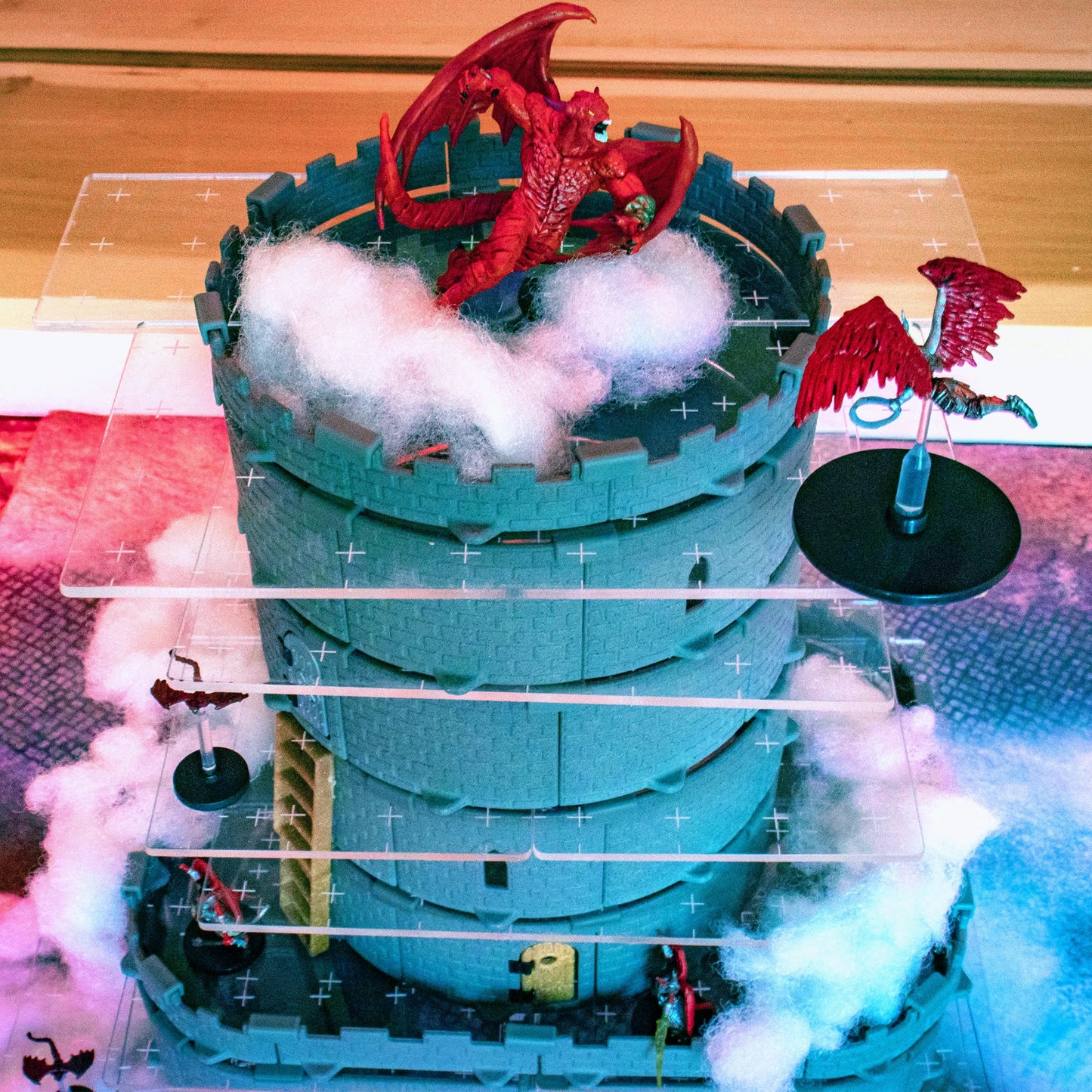 Dramatic close-up of a large dragon miniature perched on the top acrylic platform of a modular Wizard's Tower build. This highlights the stability and vertical combat potential of the terrain.