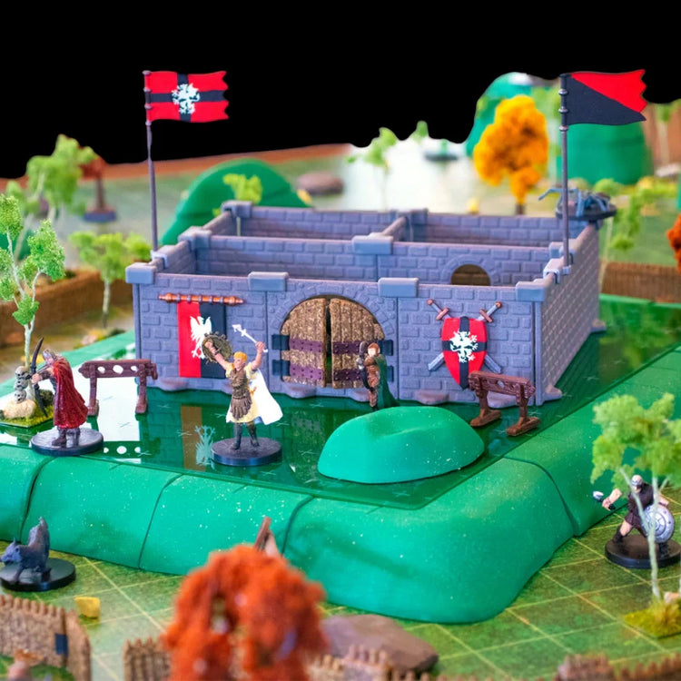 A scene of a Mini Ruins Kit decorated with painted pieces from a Castle Decor Kit built atop a plateau from the Chimera Terrain Core Set with a forest around it, demonstrating the verticality of the terrain sets.
