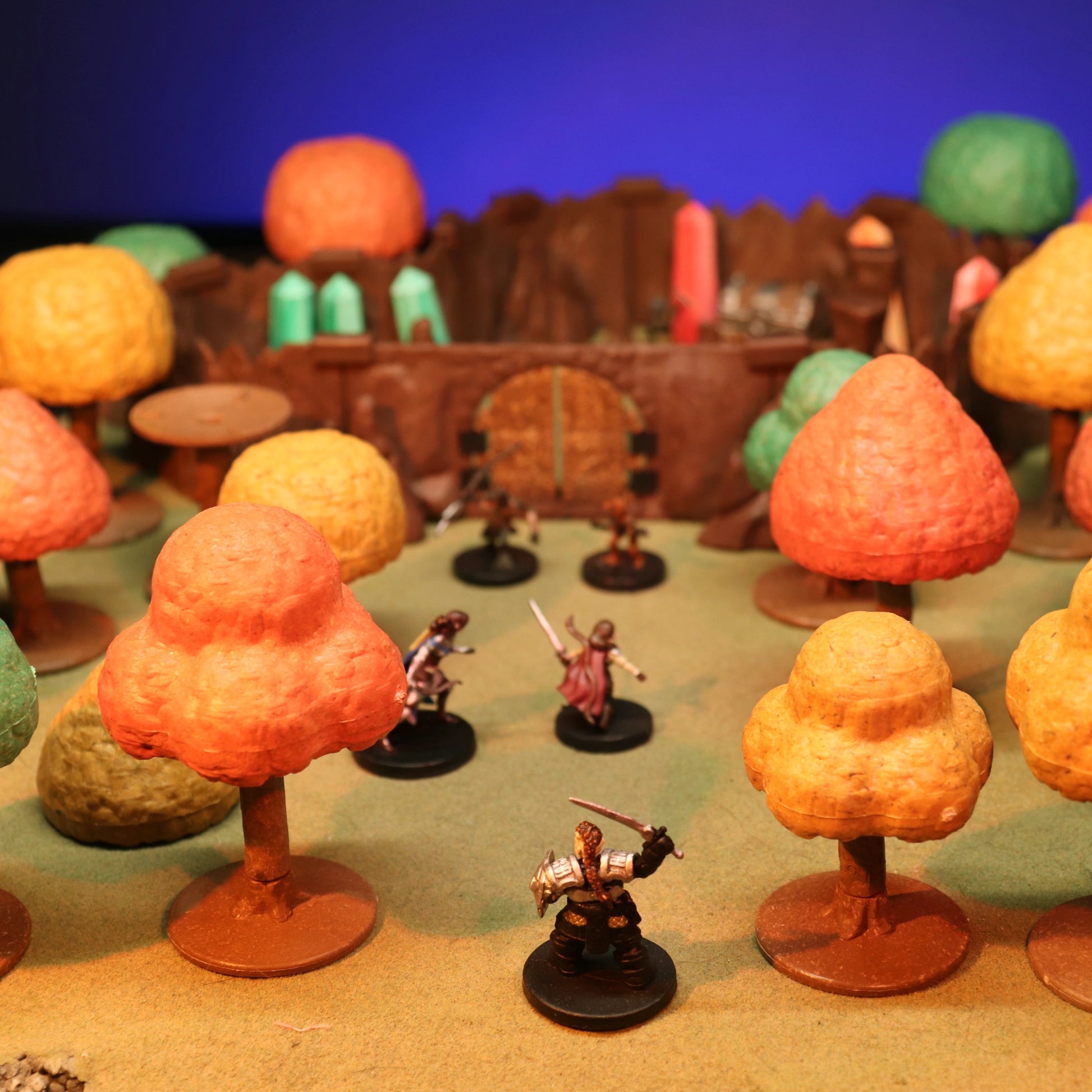 A scene of several adventurers journeying through an autumn forest towards a large pair of doors built into a mountain side, and gaurded by monsters.  