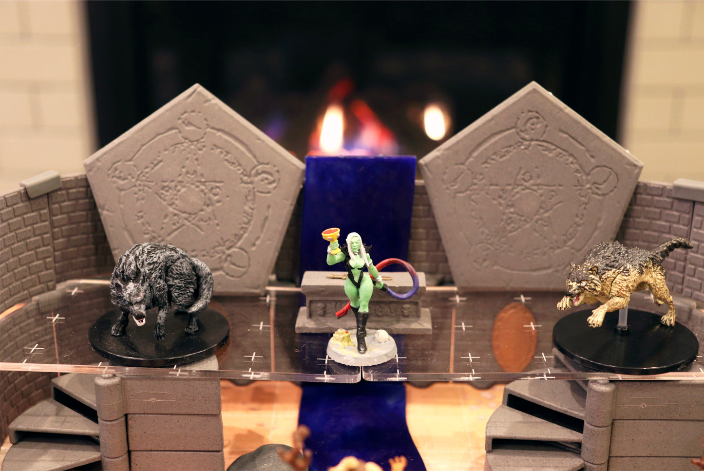Close-up scene of a sorceress miniature standing on an Altar between two Summoning Circles, flanked by two wolf miniatures in a dark dungeon setting.