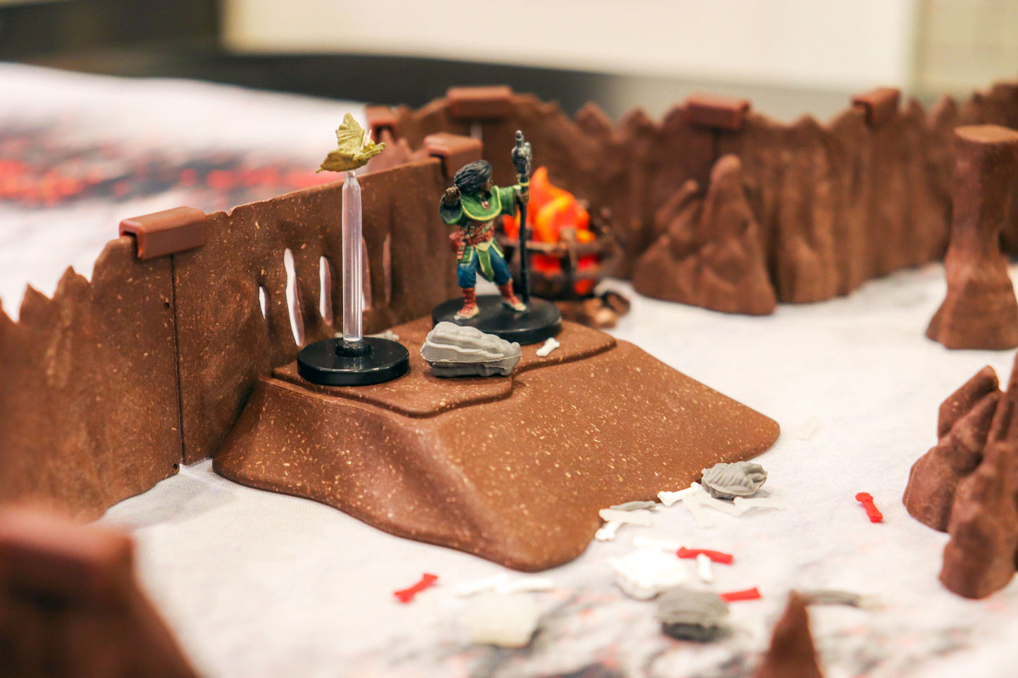 Close-up of a Dirt Ramp used as a hill on a tabletop, surrounded by cavern walls and featuring a character miniature and scatter terrain.