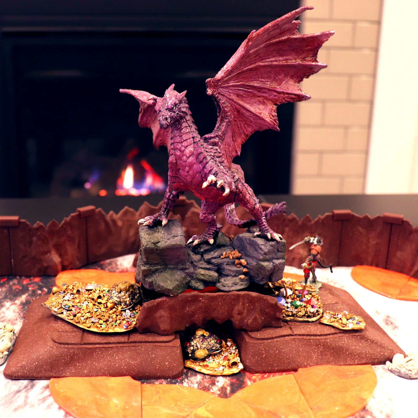 Large TTRPG setup featuring a miniature dragon perched on a Dirt Ramp section, which hides a treasure hoard beneath its archway.