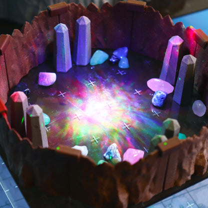 Close-up of Obelisk scatter terrain pieces and colored gemstones inside modular cavern walls, illuminated by a brilliant, multi-colored light effect.