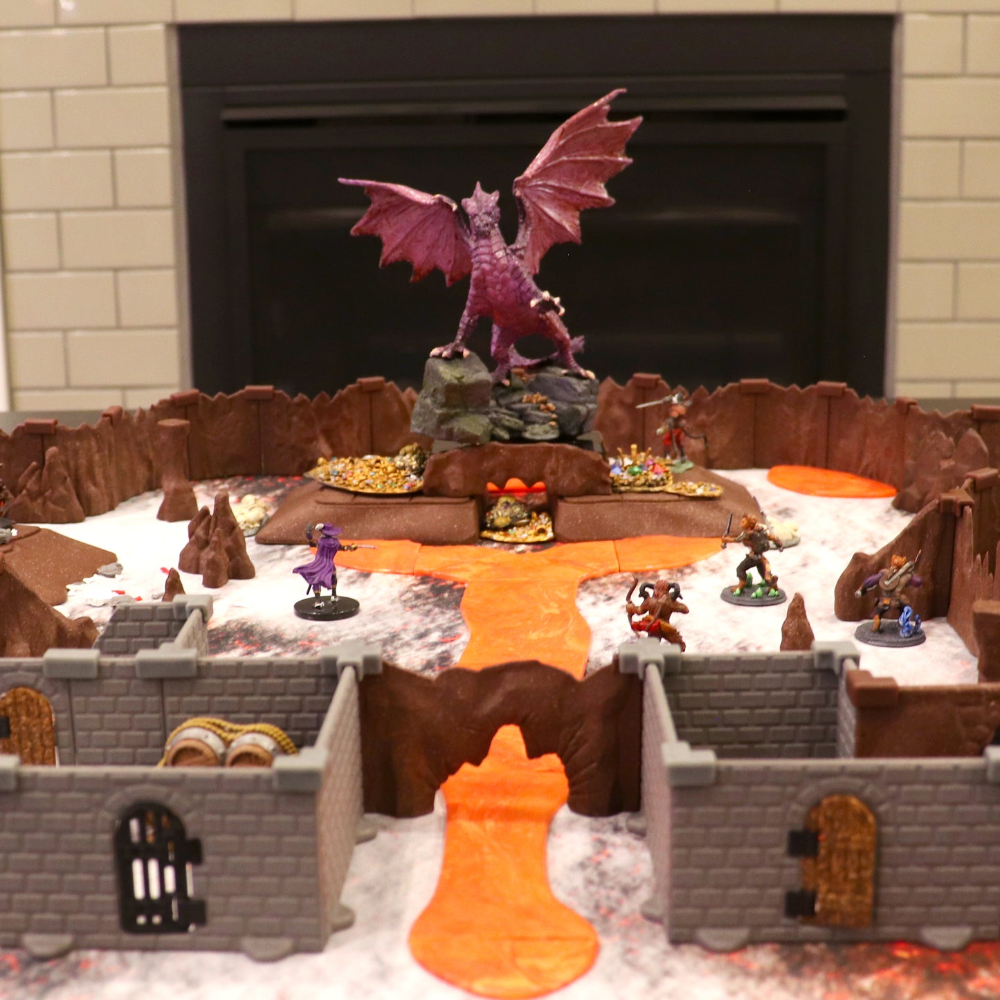 Epic TTRPG battle scene showing miniatures facing a large dragon miniature on a lava terrain path, partially enclosed by the Cavern Walls Expansion and Castle Walls.