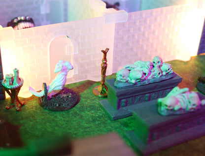 Close-up scene of two tomb altars piled with skulls and bones, standing near a white statue miniature and a lighted dungeon archway, perfect for a necromancer encounter.