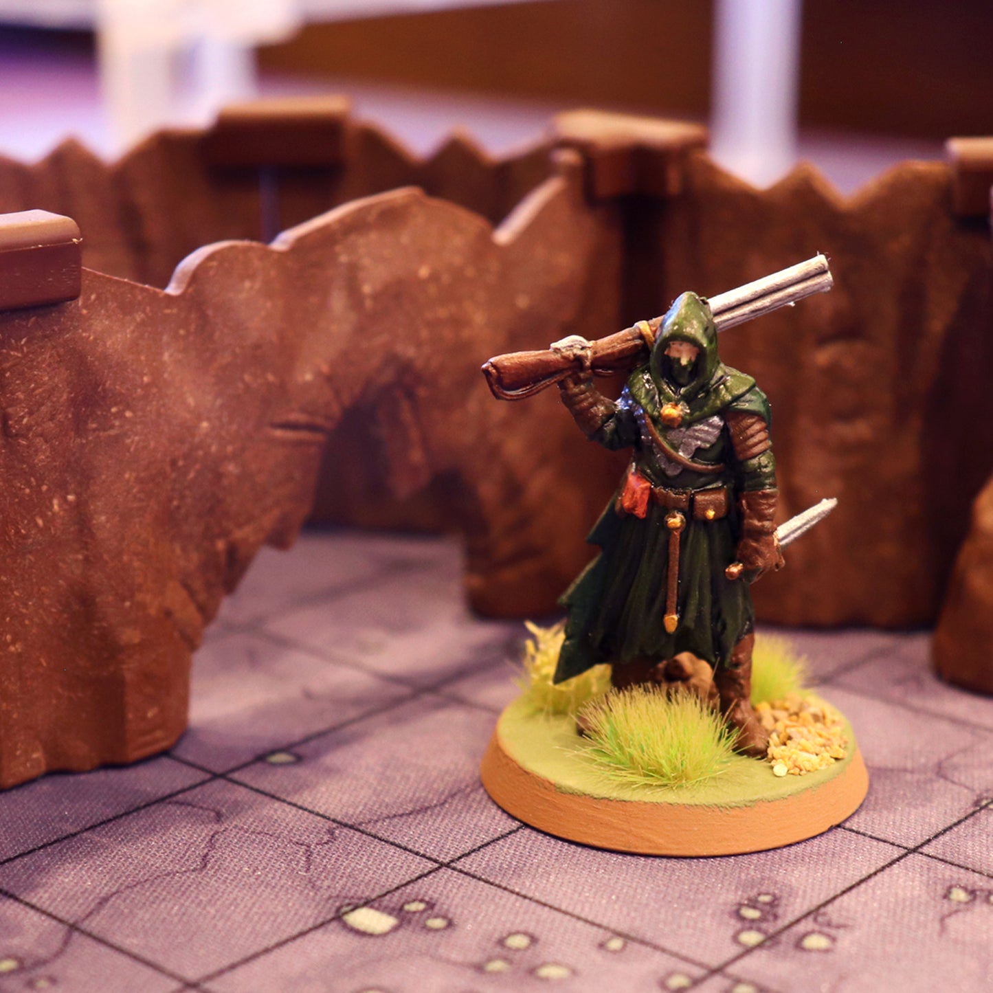Close-up shot of a ranger miniature with a rifle standing next to a Bottom Opening wall from the Special Cavern Walls Expansion terrain set.