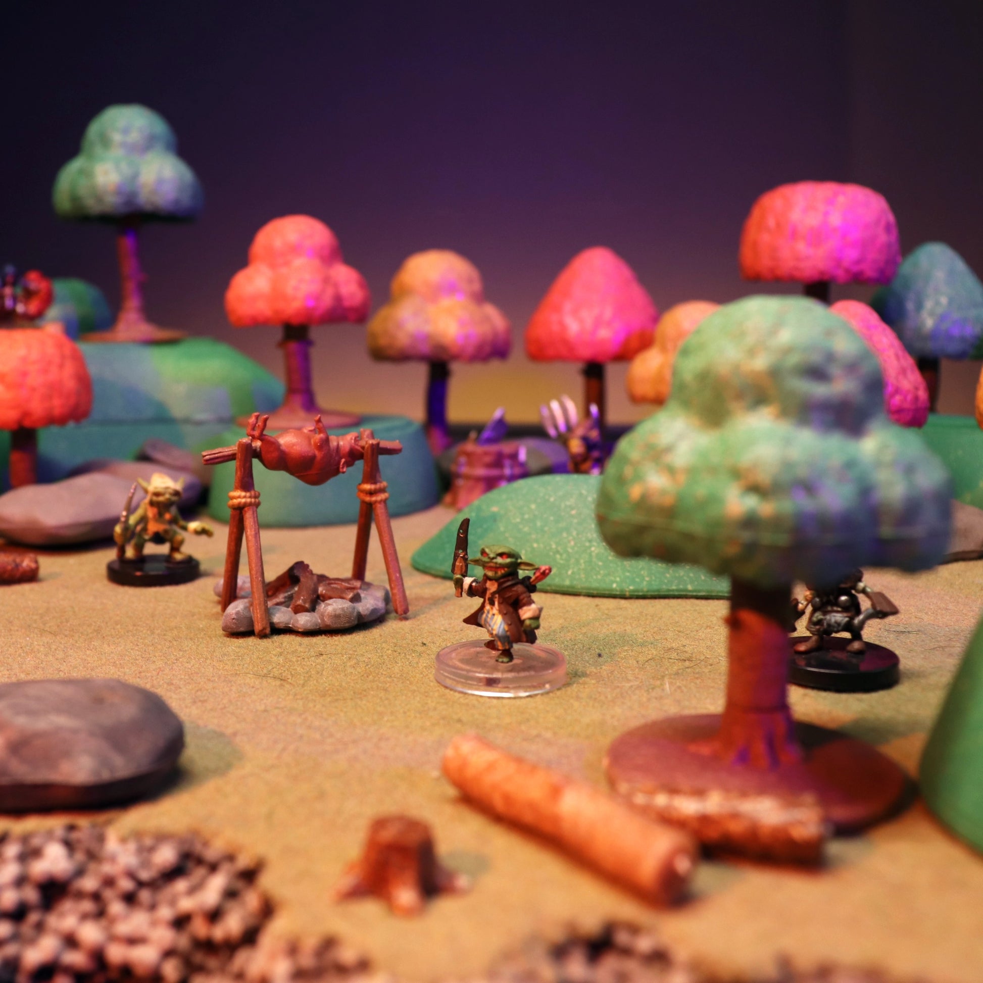 Autumn forest camp scene with a cooking spit and campfire accessory, surrounded by modular trees and various miniatures.