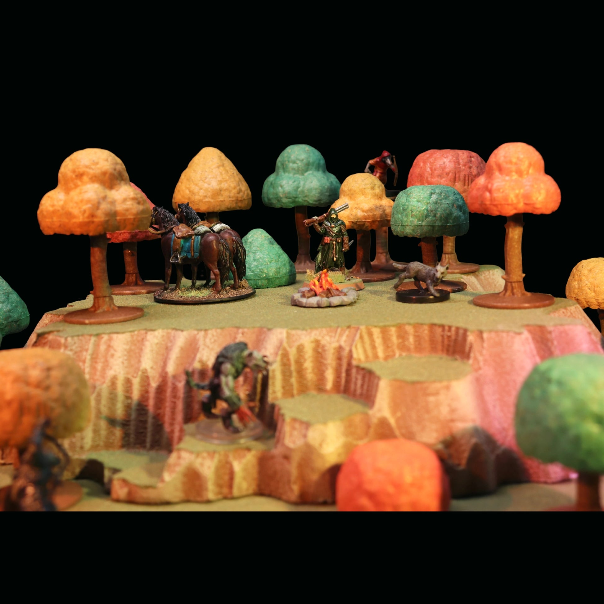 Autumn-hued forest terrain scene with a mounted miniature, campfire, and warrior miniatures among the modular trees.