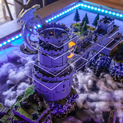 Overview of a large rpg dungeon battle featuring a very tall dragons tower made by using clear acrylic multi-level platforms to maintain visibility of the map tiles below.