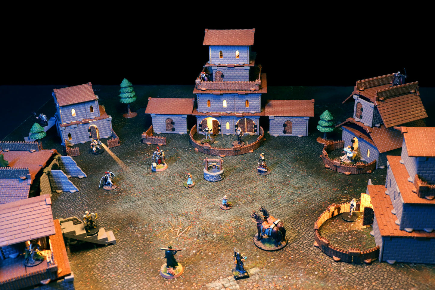 Epic fantasy village battle scene at night on a cobblestone map, featuring multi-story 3D buildings with brown Village Roof Kit tiles.