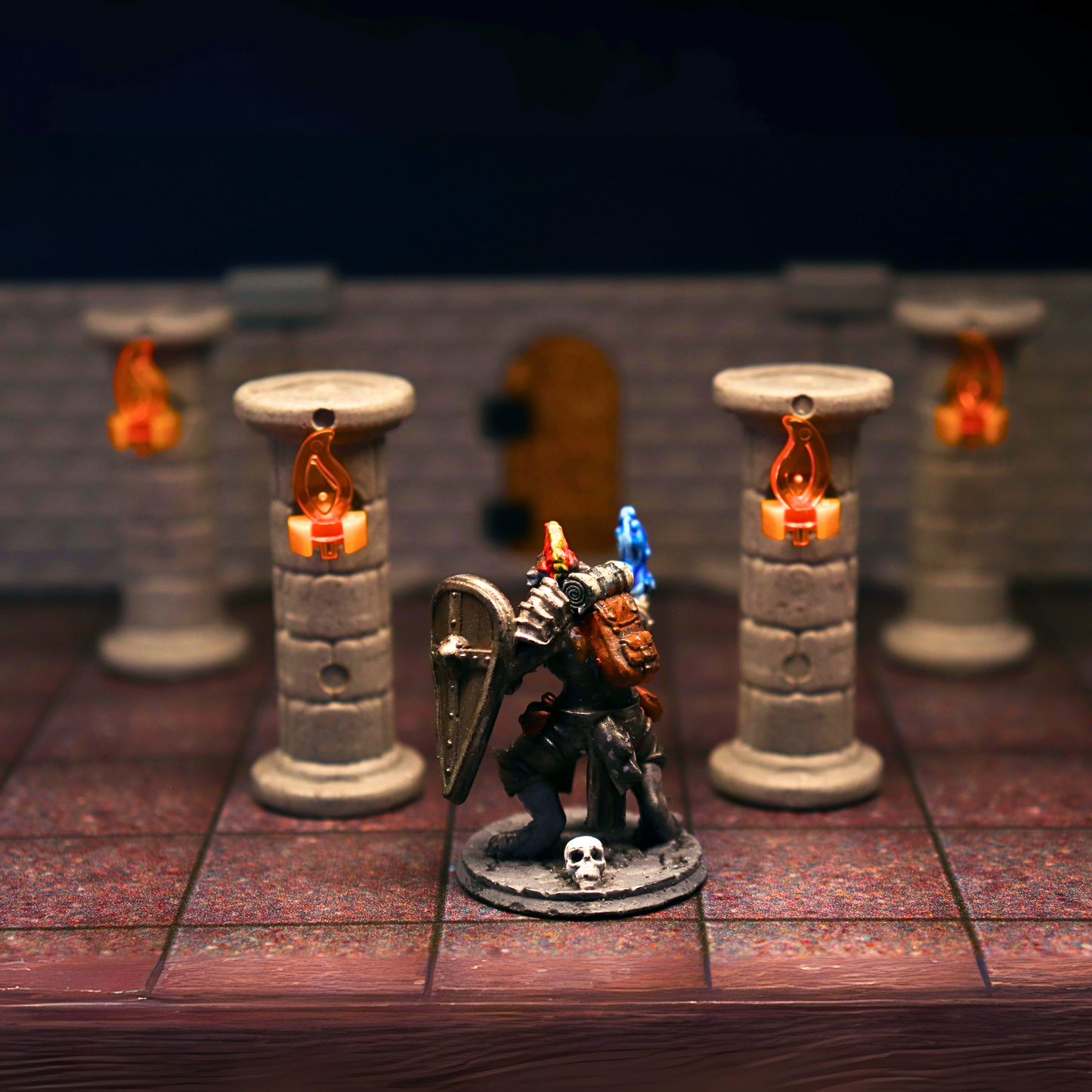 Painted knight miniature with a shield, posed in a dungeon setting with stone pillars and warm torches in the background.