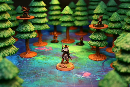 A ranger miniature standing in a dark forest with two other miniatures placed on high-ground tree platforms using the modular trees.