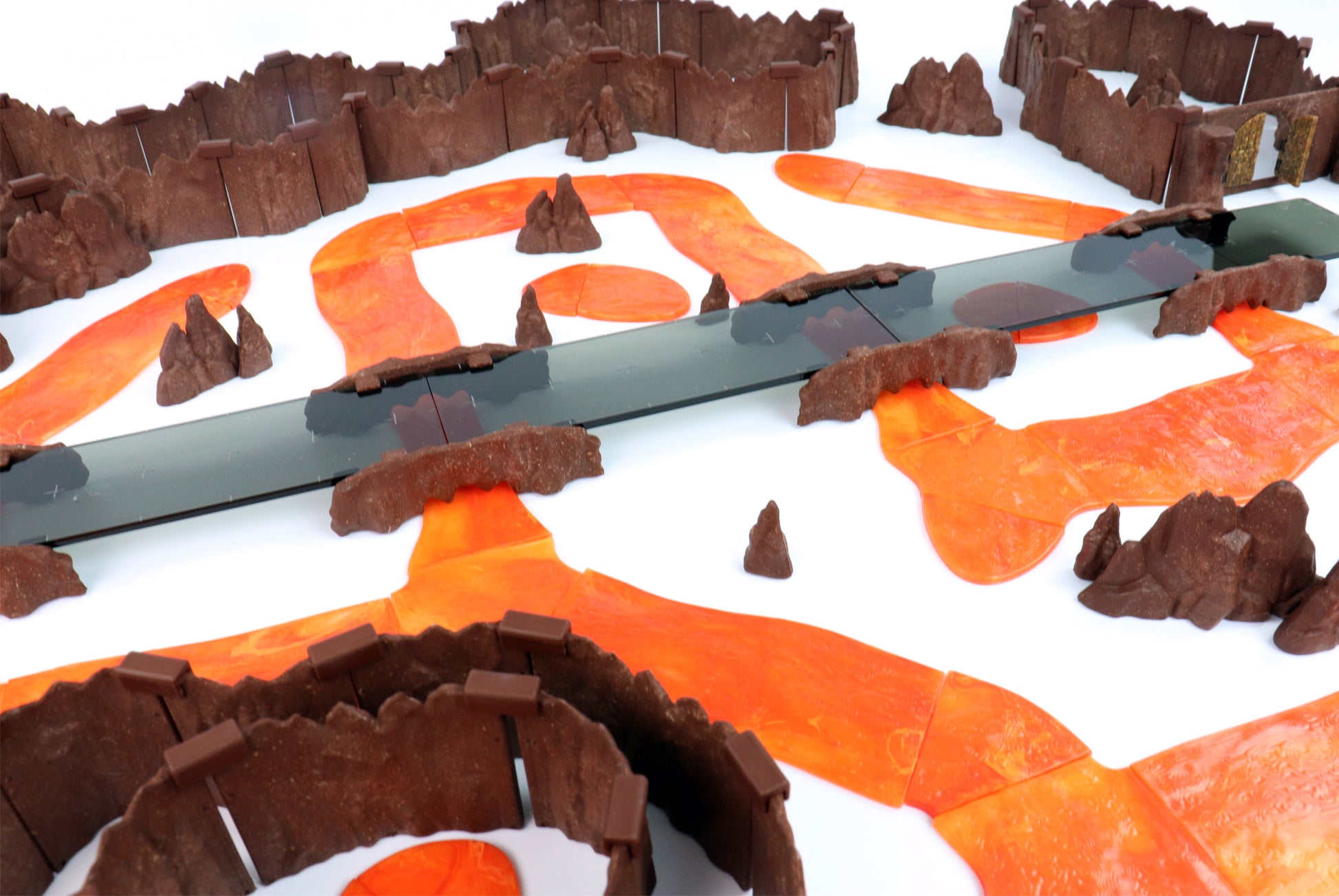 A winding lava river with multiple Rock Bridge Kits crossing it in various points on a white background, highlighting the color and texture of the Lava River pieces.