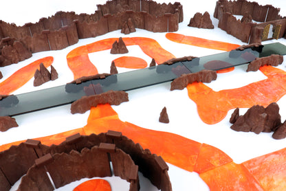 A winding lava river with multiple Rock Bridge Kits crossing it in various points on a white background, highlighting the color and texture of the Lava River pieces.