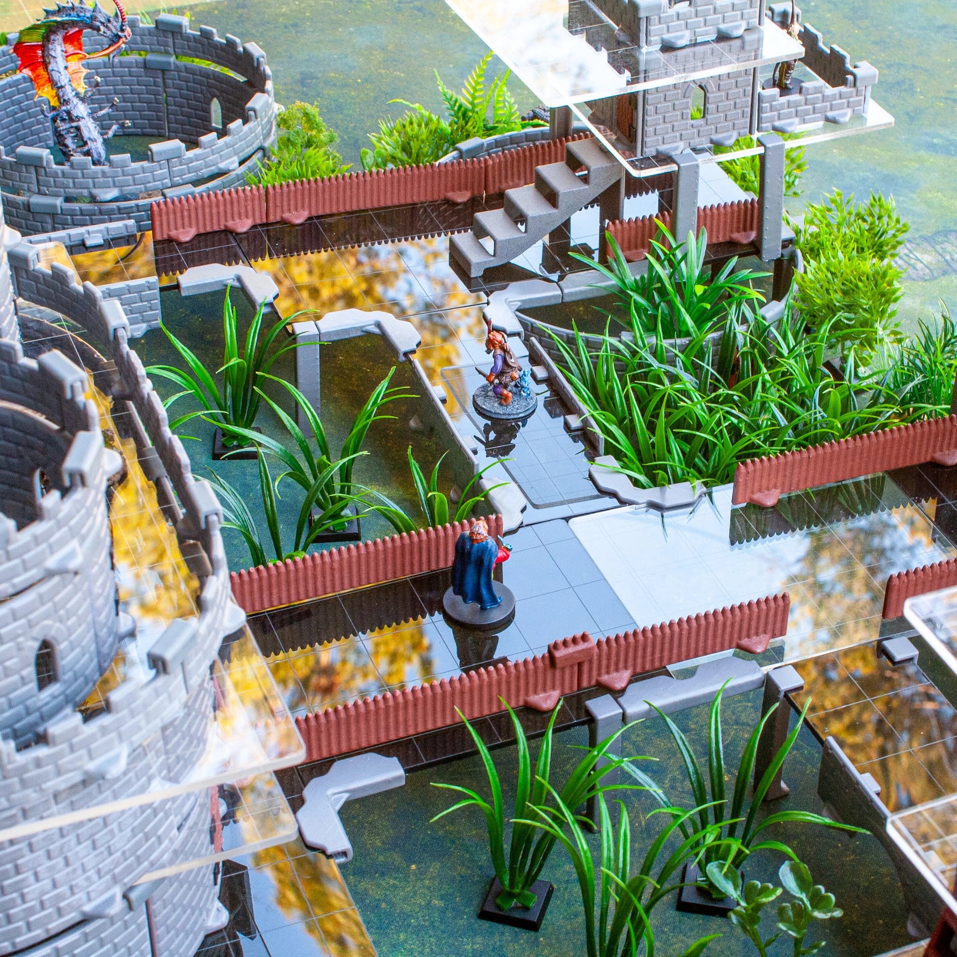 Miniatures positioned on dark gray acrylic platform bridges between multiple towers in a dungeon encounter, maintaining visibility of the map tiles below.