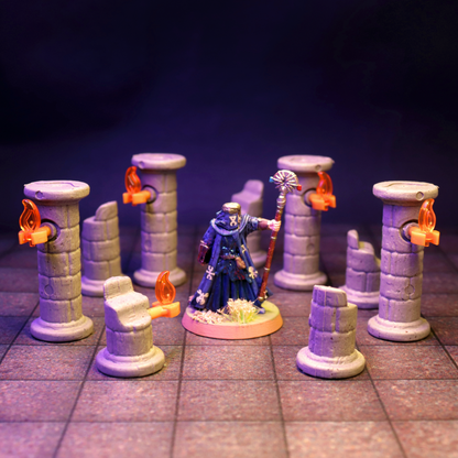 Wizard or sorcerer miniature standing amongst a mix of full and broken stone pillars with torches, set on a grid map with blue lighting.