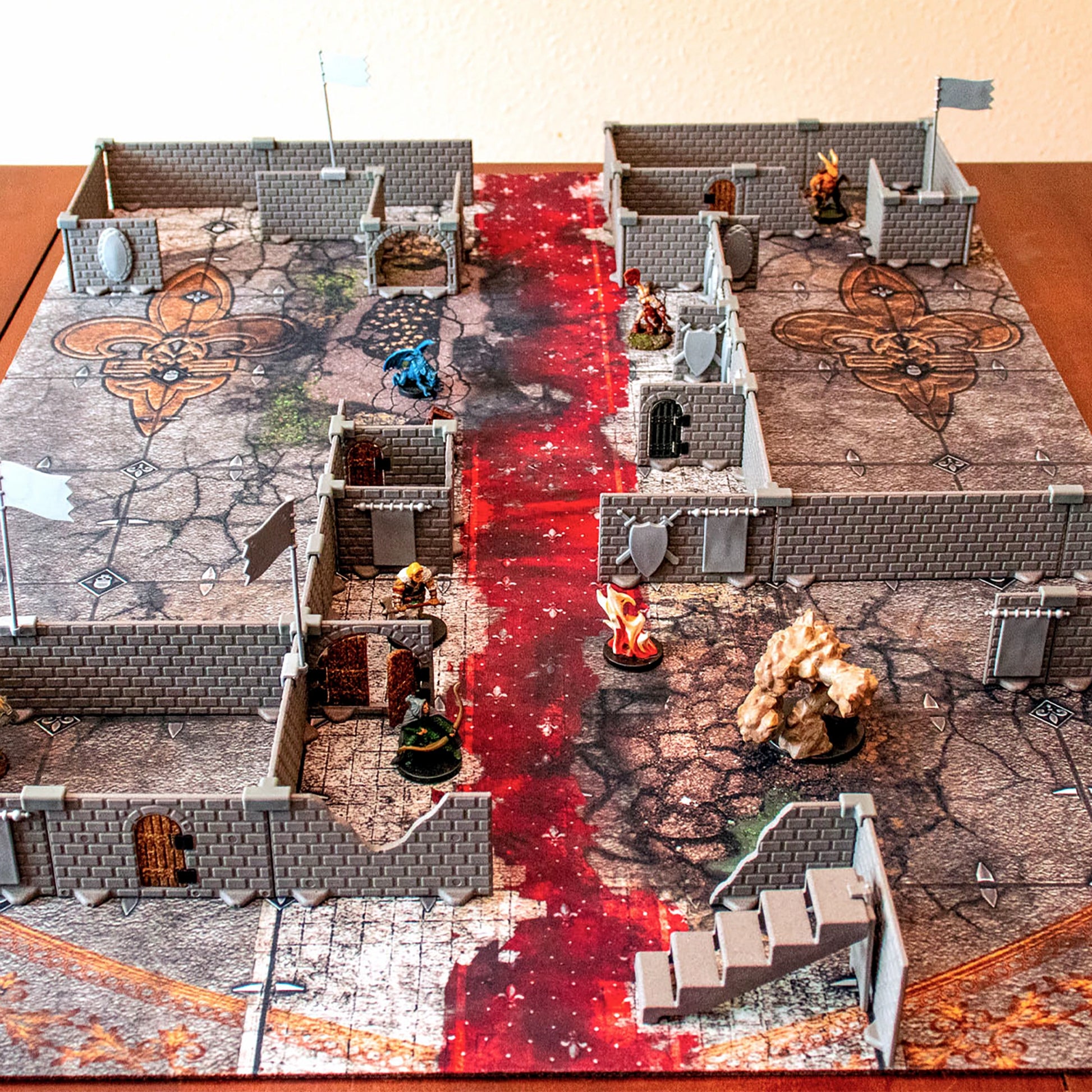 Overhead view of a large, complex modular dungeon layout assembled with the Squire set on a fantasy battlemap. The scene includes various corridors, chambers, doors, stairs, and a collection of Dungeons & Dragons or tabletop RPG miniatures and terrain.