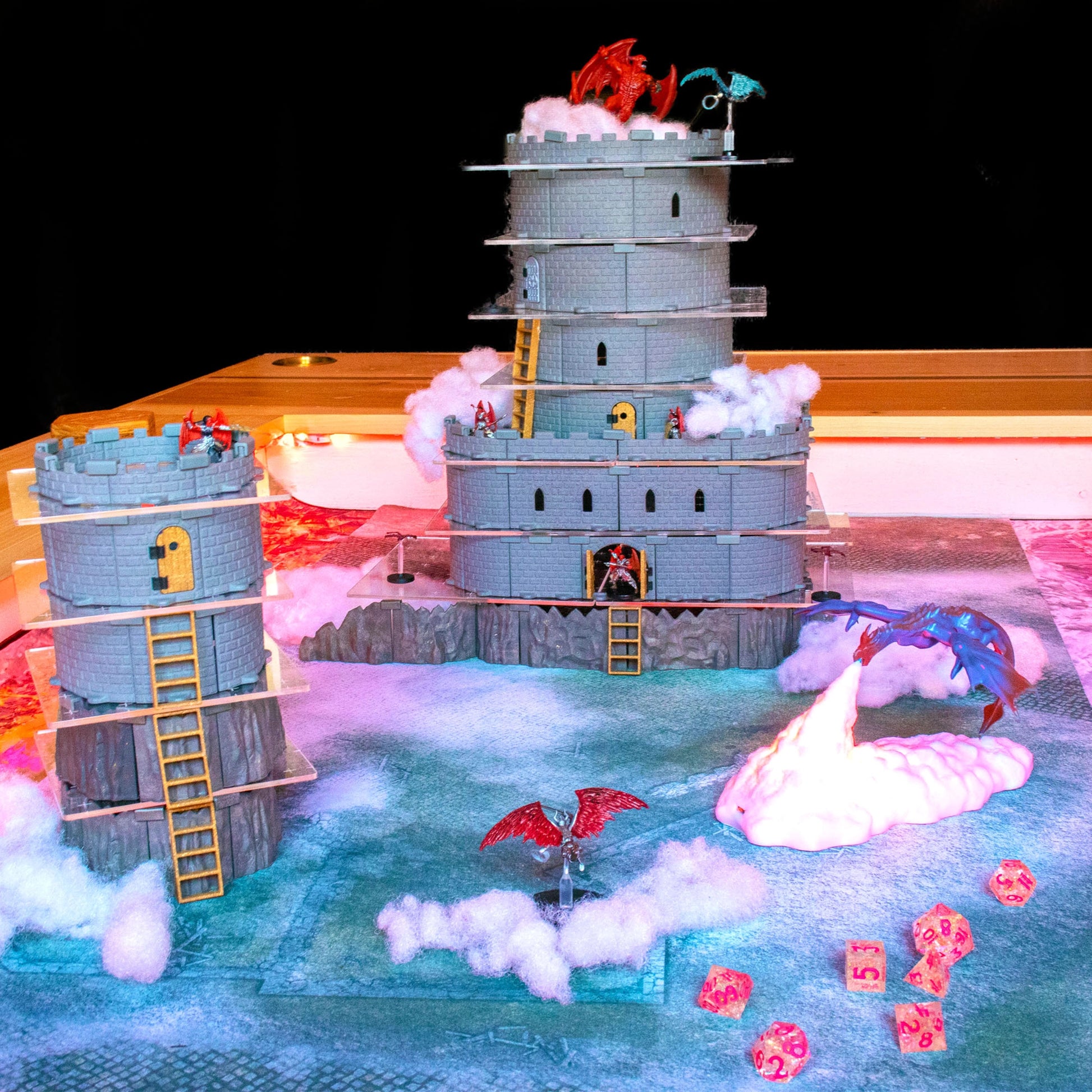 Full assembly shot of the modular Wizard's Tower Set on a mist or cloud background, showcasing a tall, imposing, multi-level castle tower build with various windows and walls, all perched atop a Goblin Cavern Set.